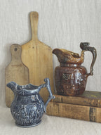 Vintage Wood and Sons blue relief jug shown beside a brown treacle glaze jug on a bread board, for size reference