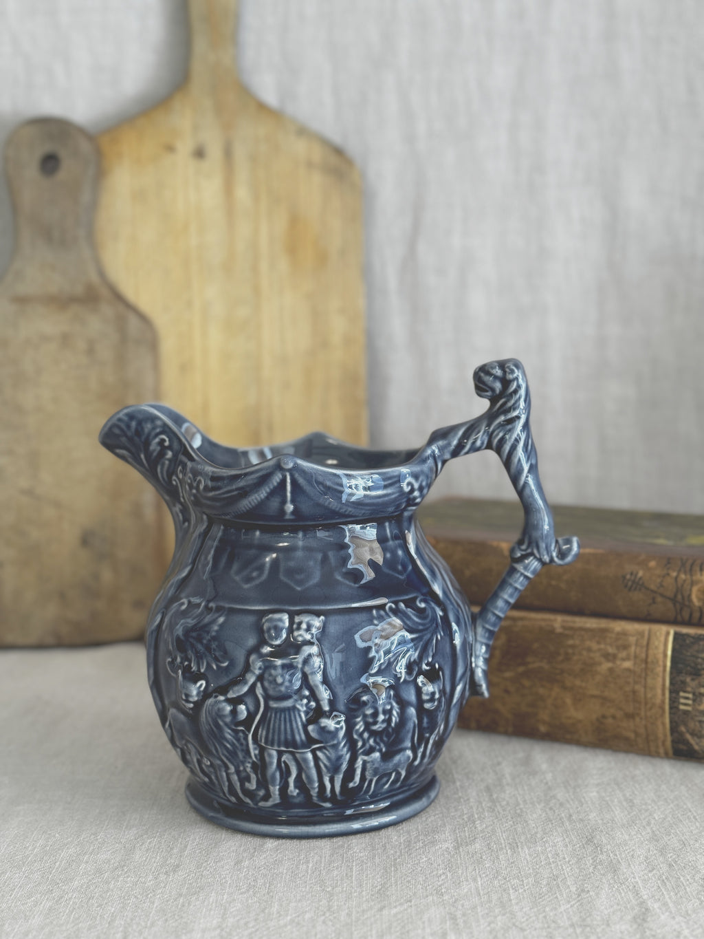 Vintage English blue relief jug with mask handle, shown against a bread board and antique books for scale