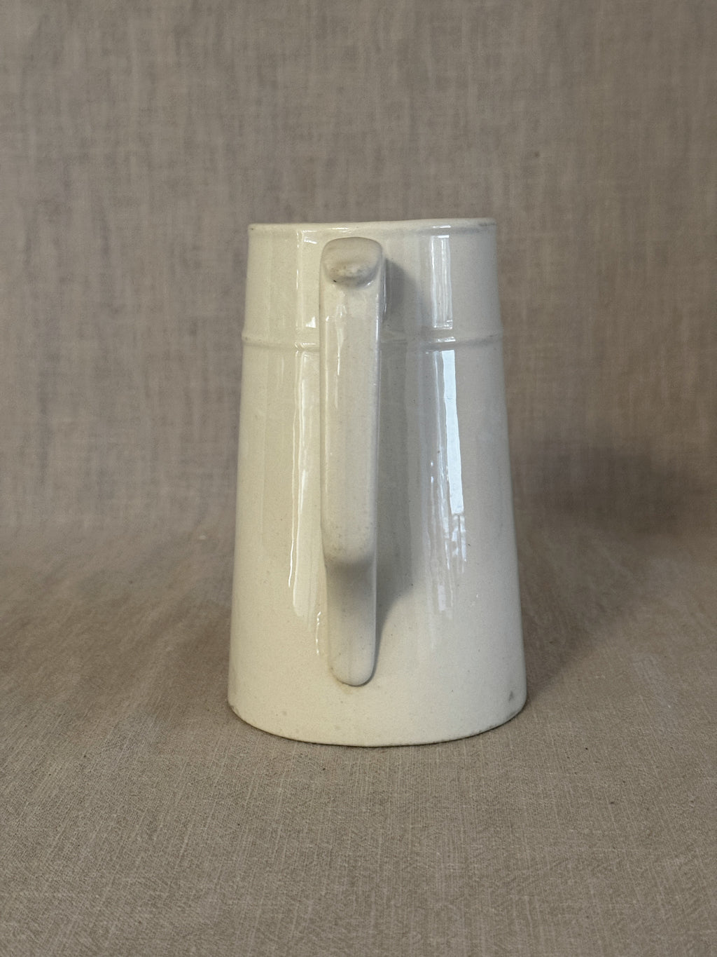 Front view of the small white jug showing the spout and the raised band at the neck