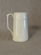 Side view of the small white earthenware jug showing its straight tapered form