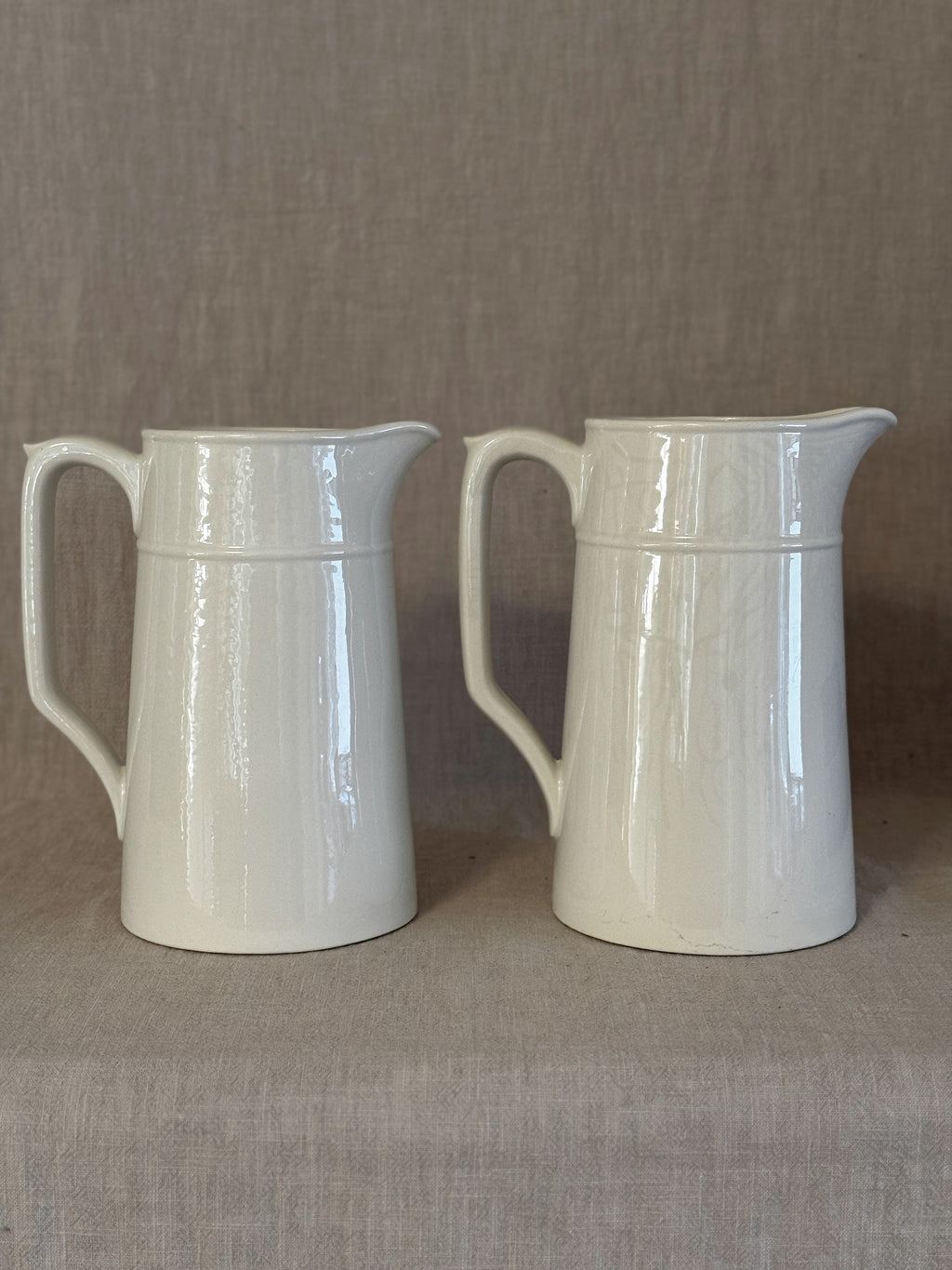 Both tall white jugs seen from the front, showing their identical form