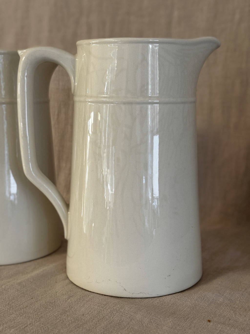 Detail of the tall white jug showing the spout and the plain glazed surface