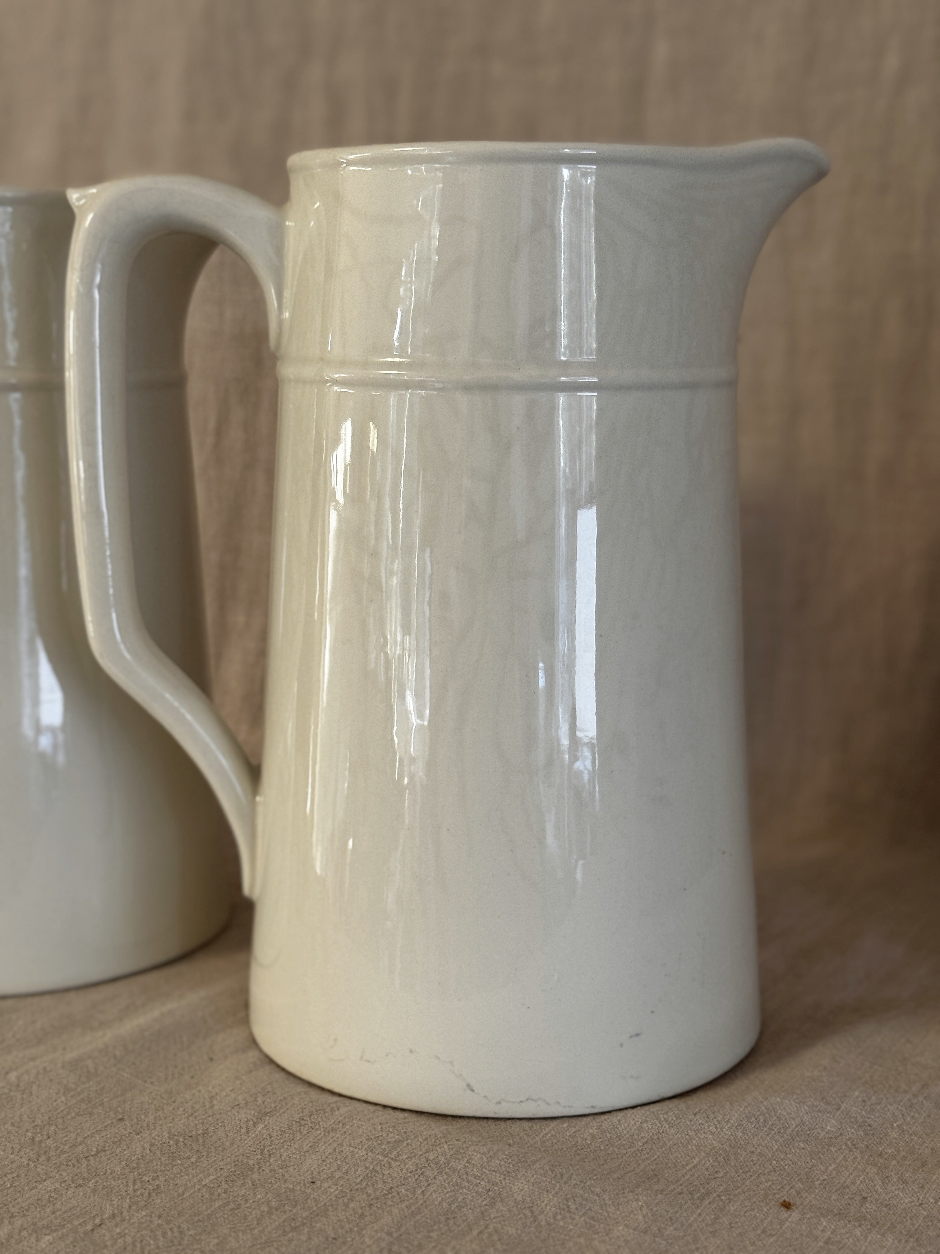 Detail of the tall white jug showing the spout and the plain glazed surface