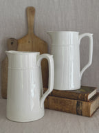 Pair of tall white Scandinavian jugs, styled with a bread board and antique books