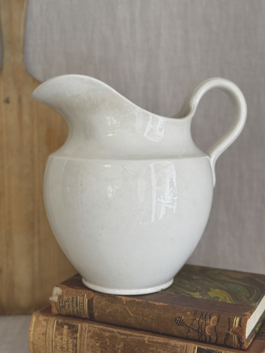 Swedish white washstand jug, styled on antique books against a wooden board