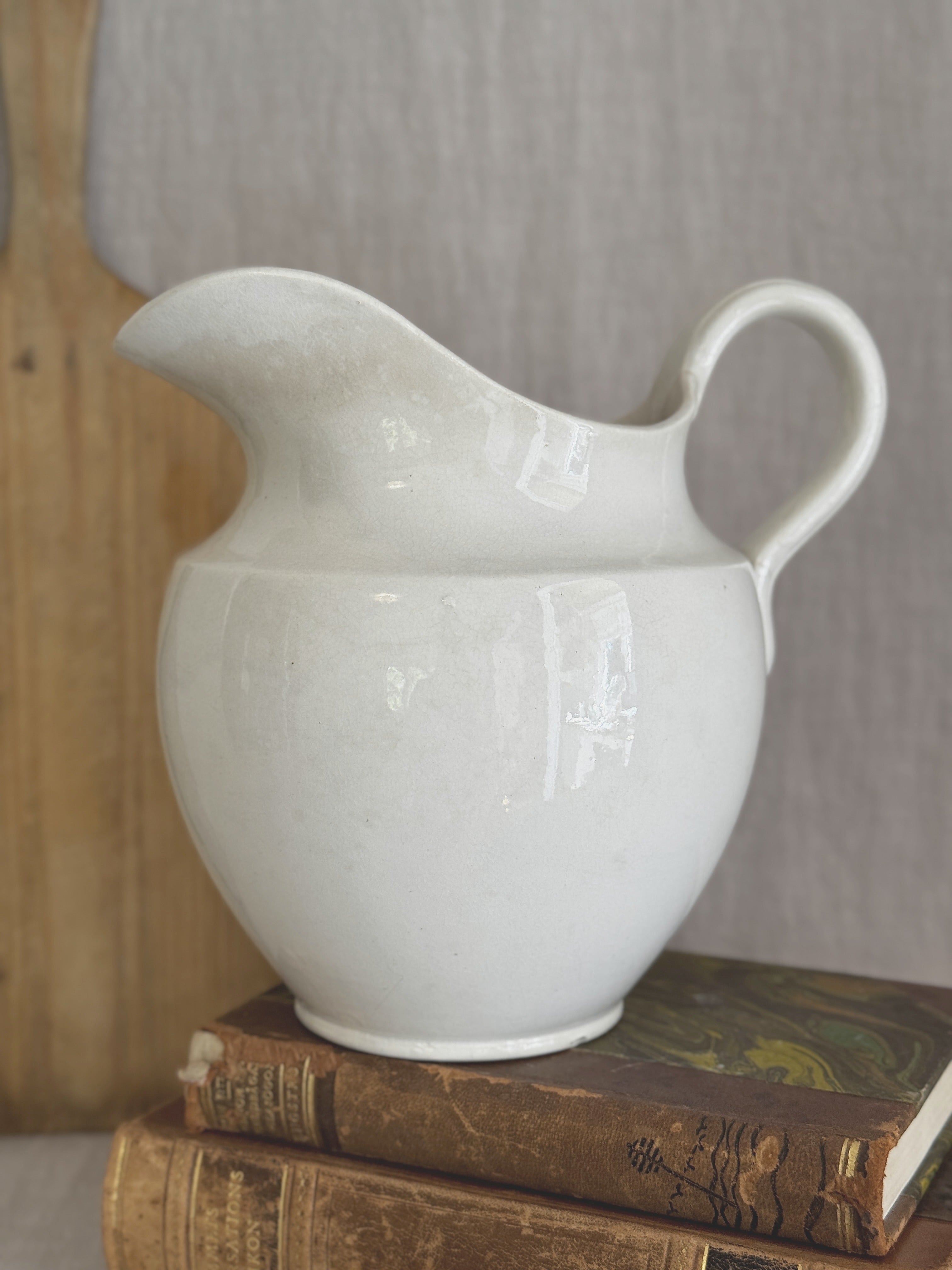 Swedish white washstand jug, styled on antique books against a wooden board