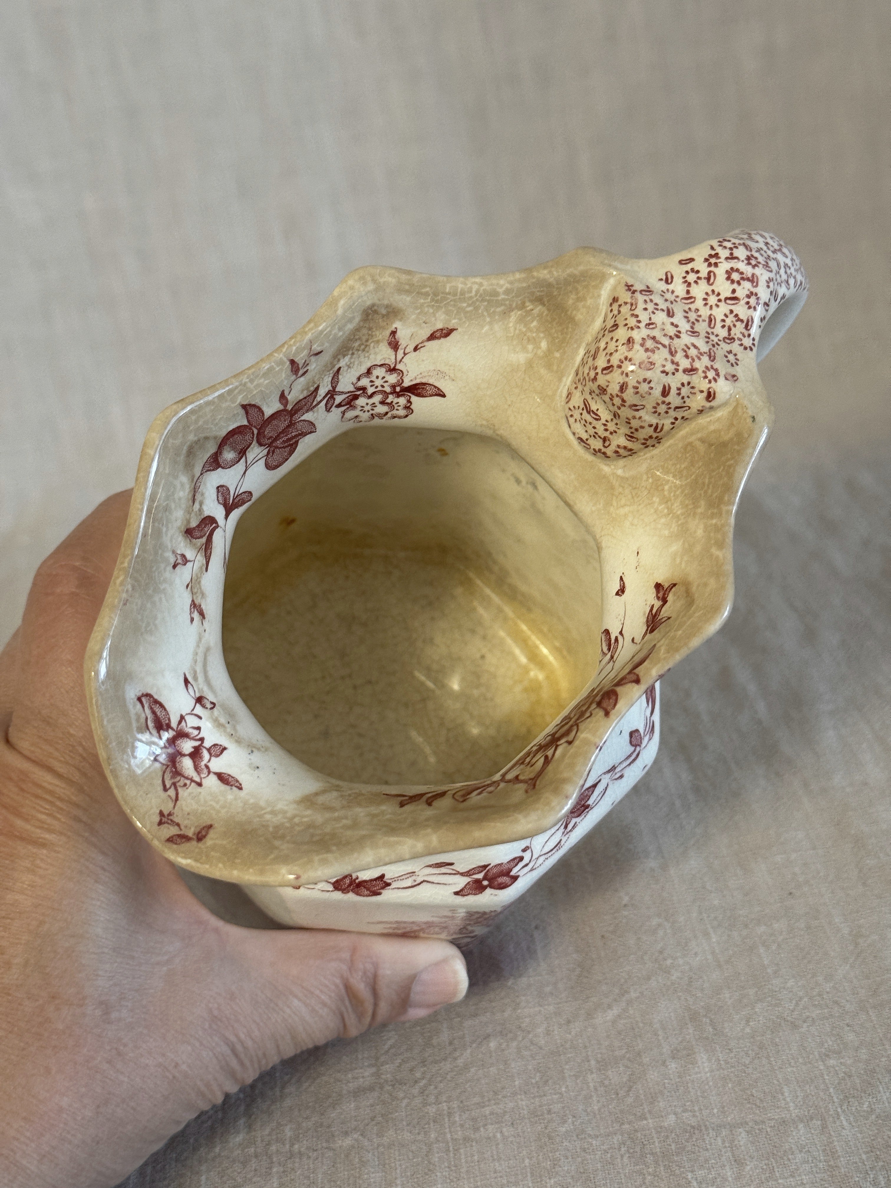 The jug held in the hand showing the interior and the scale of the piece