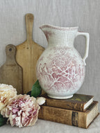 Antique French Sarreguemines Colomba jug in red transferware, styled on antique books beside a wooden bread board