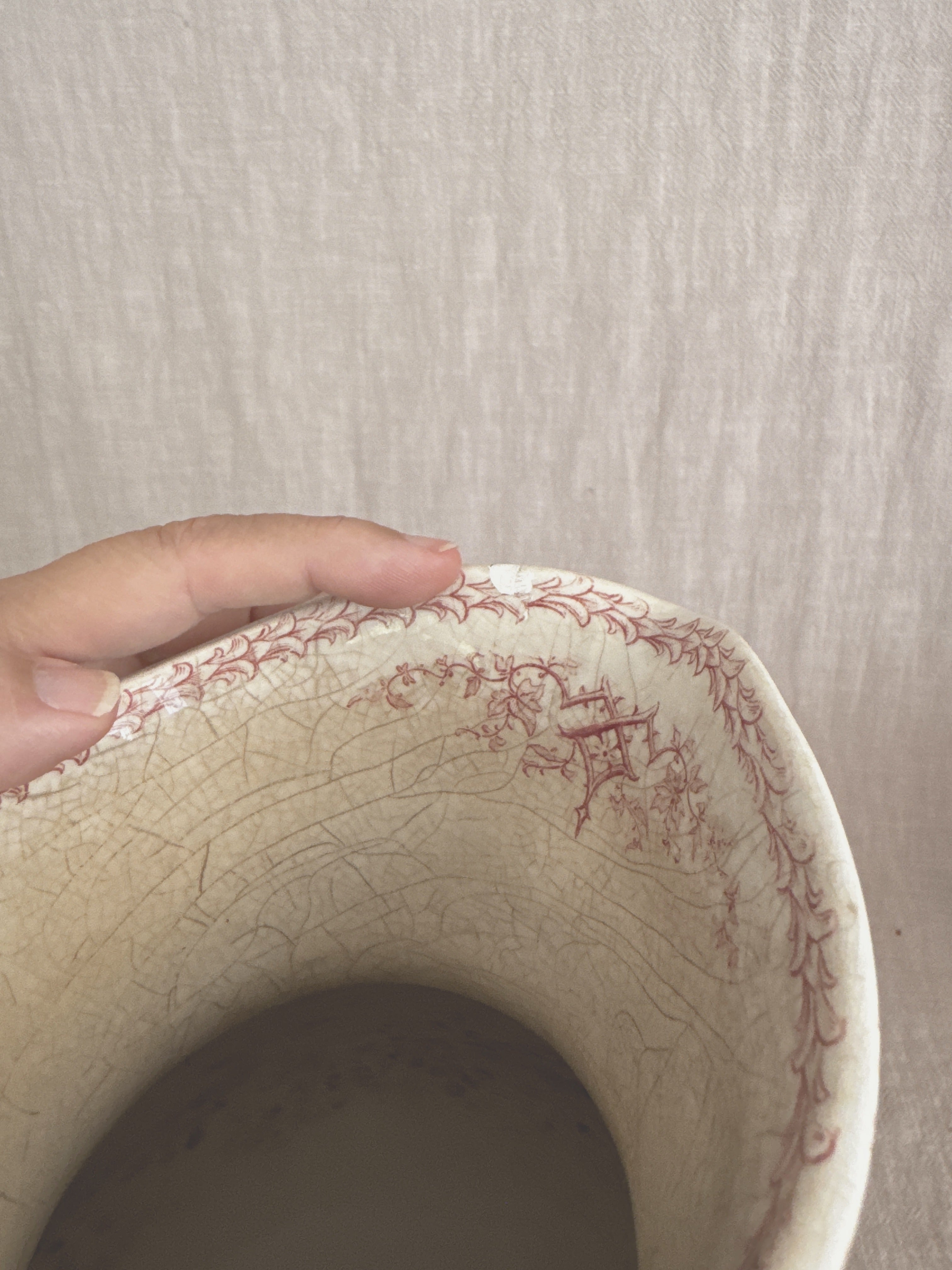 Interior of the jug held in hand, showing the cream glaze and light age staining