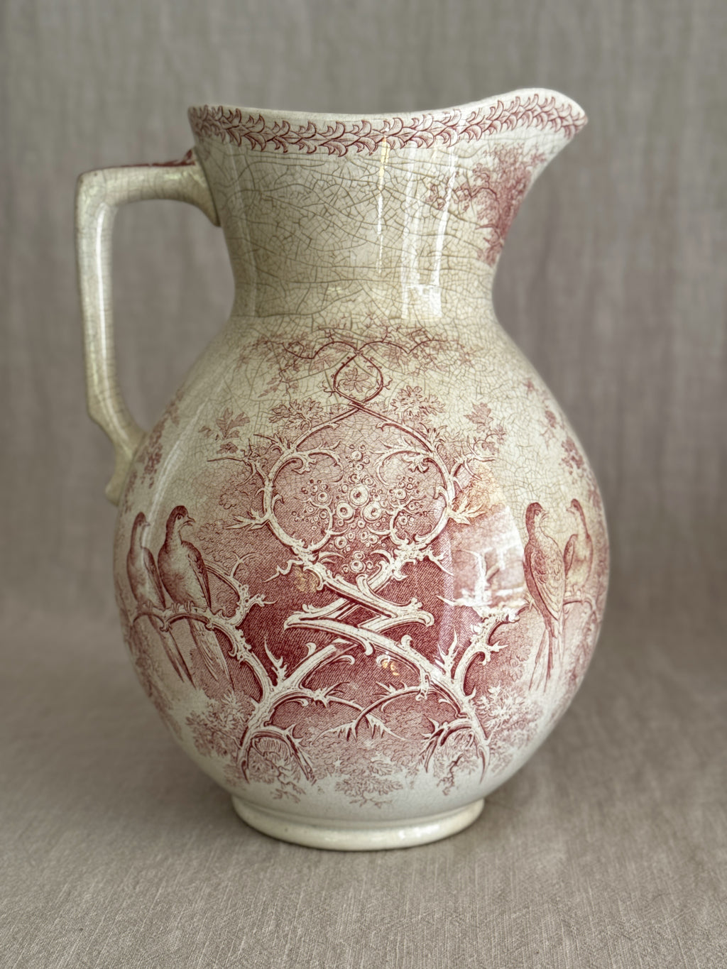 Side view of the red transferware jug showing the rounded body and low foot
