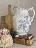 Large Belgian purple transferware jug with passionflowers, styled on antique books beside a wooden bread board