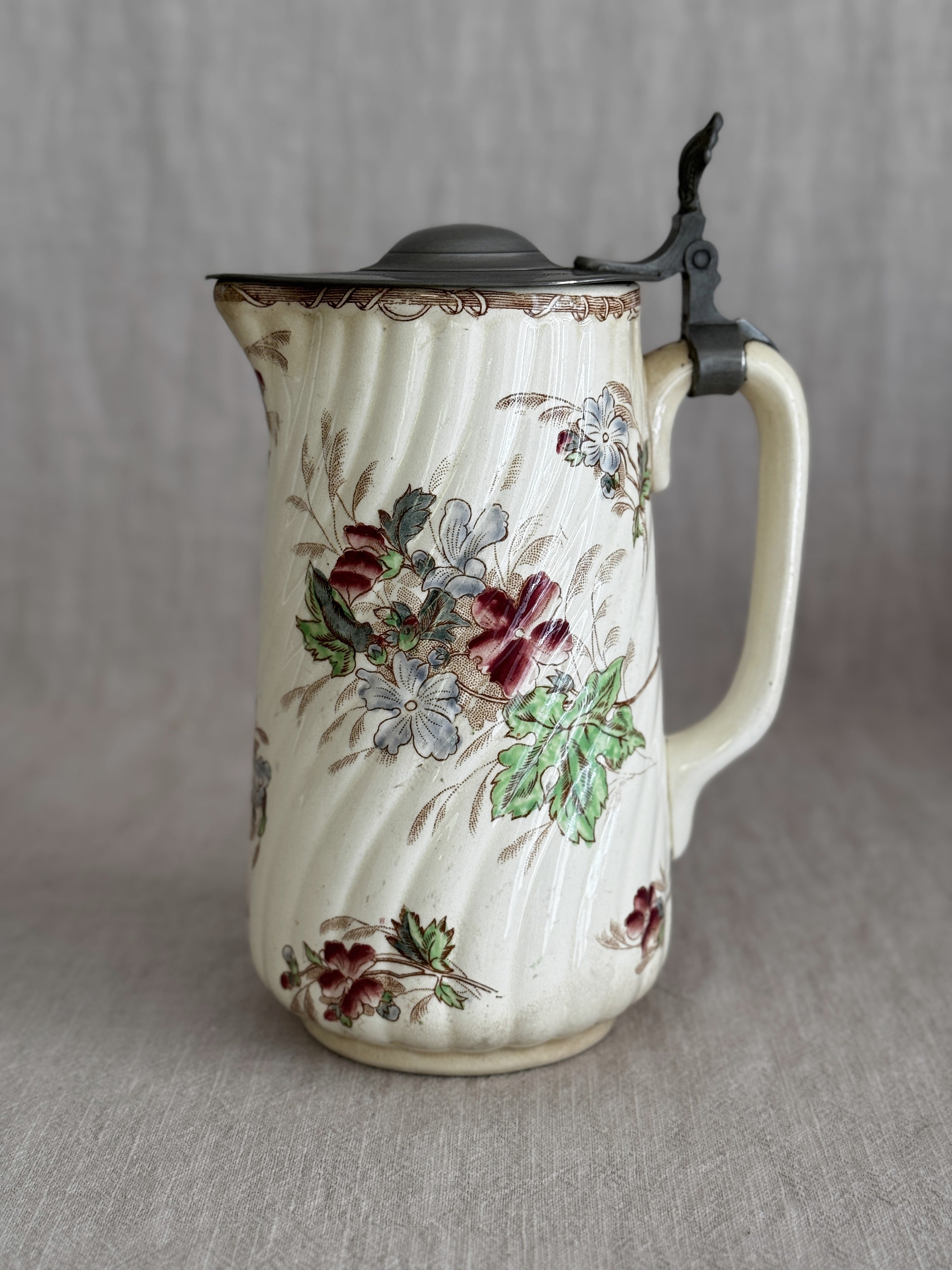 Front view of the ribbed faience jug with pewter lid and polychrome floral decoration