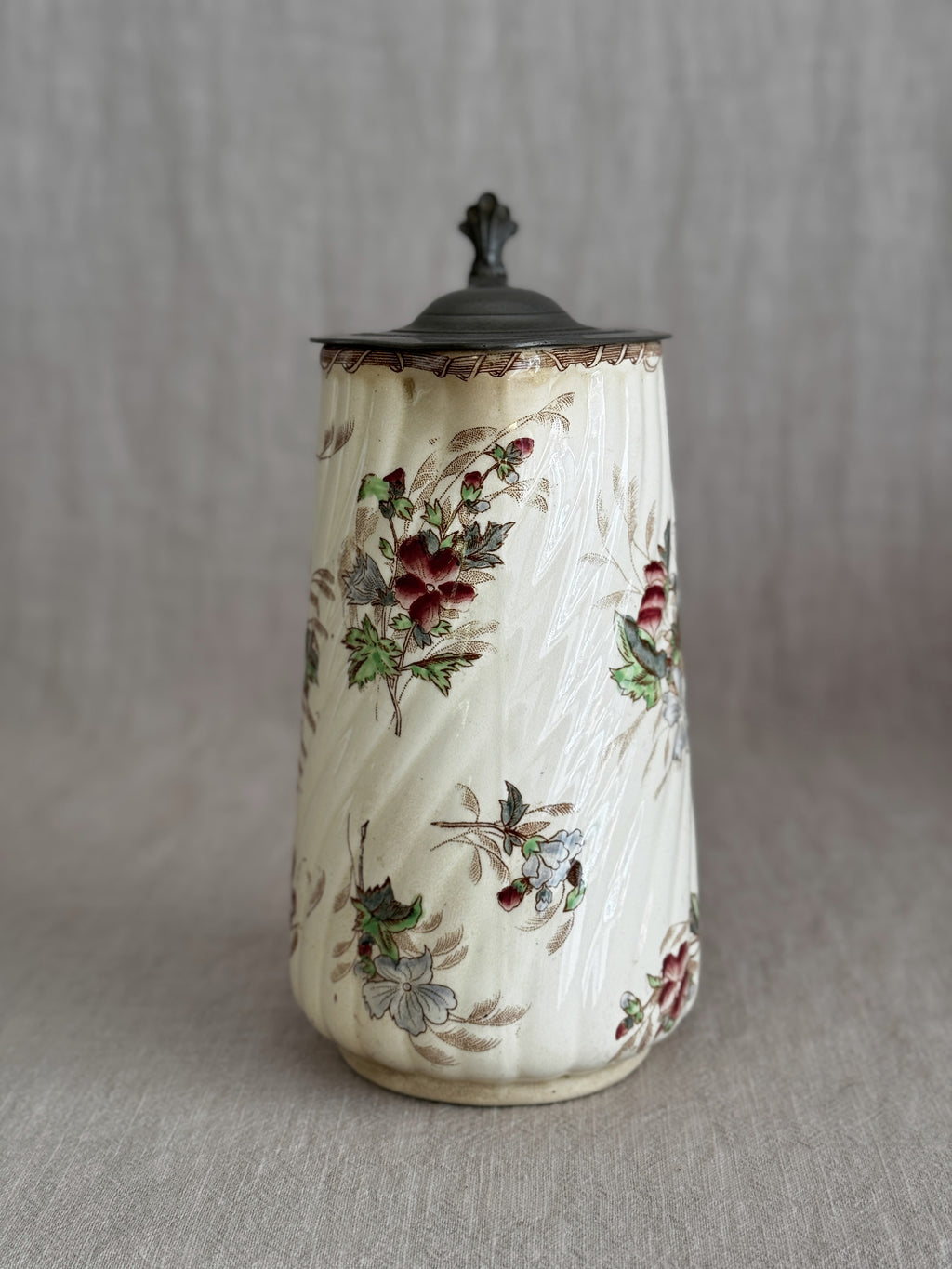 Full view of the jug with the pewter lid closed and the hand-coloured floral sprays visible