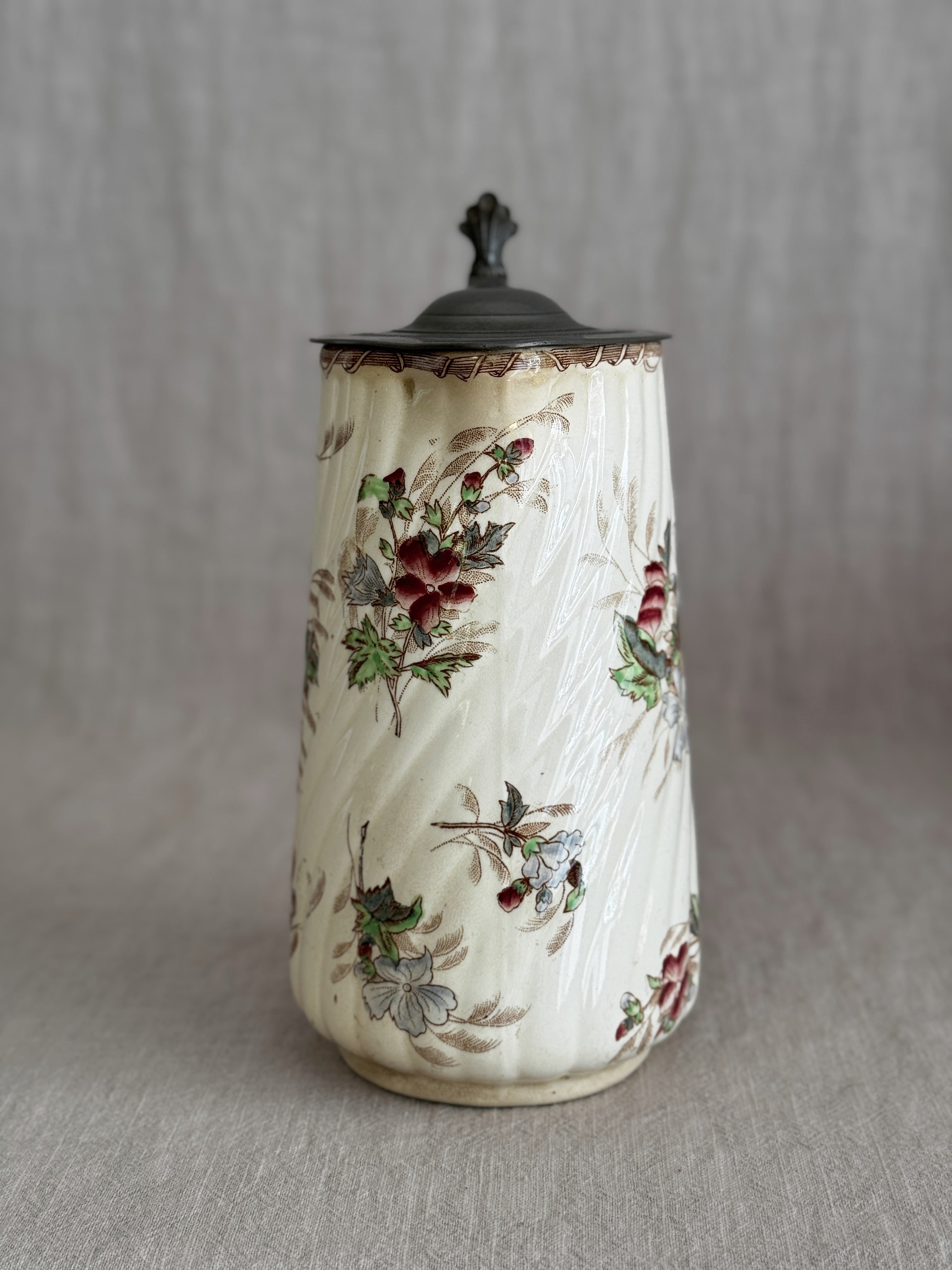 Full view of the jug with the pewter lid closed and the hand-coloured floral sprays visible