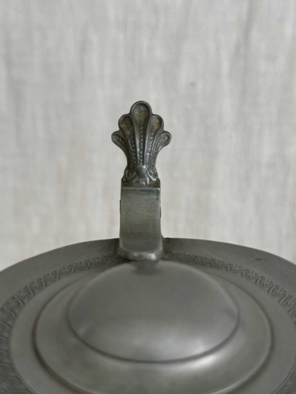 Detail of the pewter lid showing the moulded border and cast thumbpiece