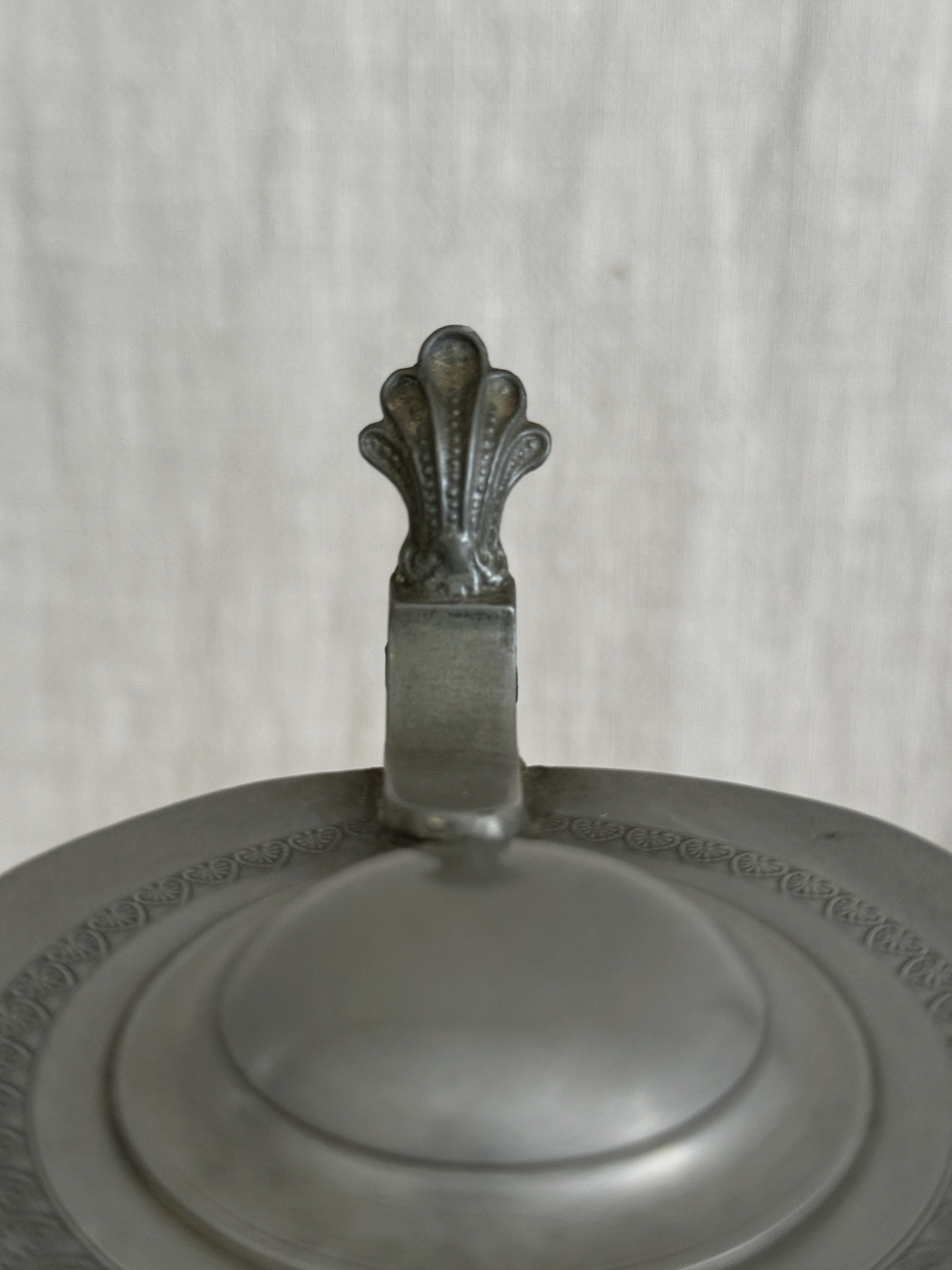 Detail of the pewter lid showing the moulded border and cast thumbpiece