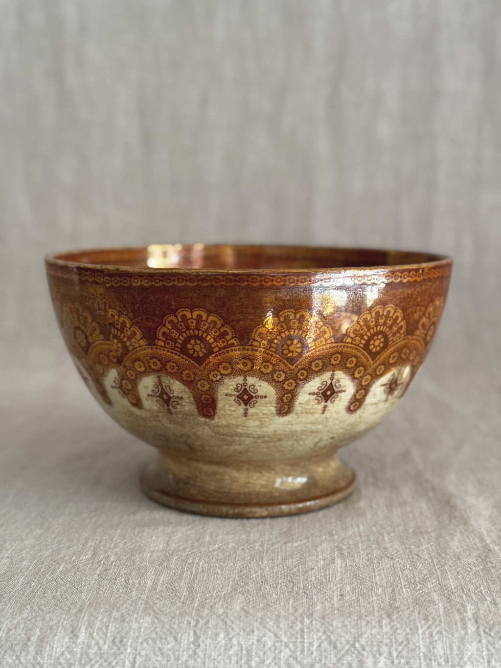 Side view of the copper lustre bowl showing the gold glaze and printed rust border on the pedestal foot