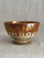 Side view of the copper lustre bowl showing the gold glaze and printed rust border on the pedestal foot