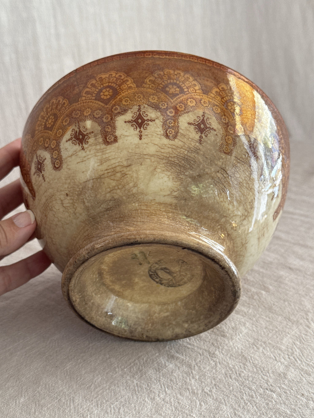 The bowl held in hand and tipped to show the underside and foot ring
