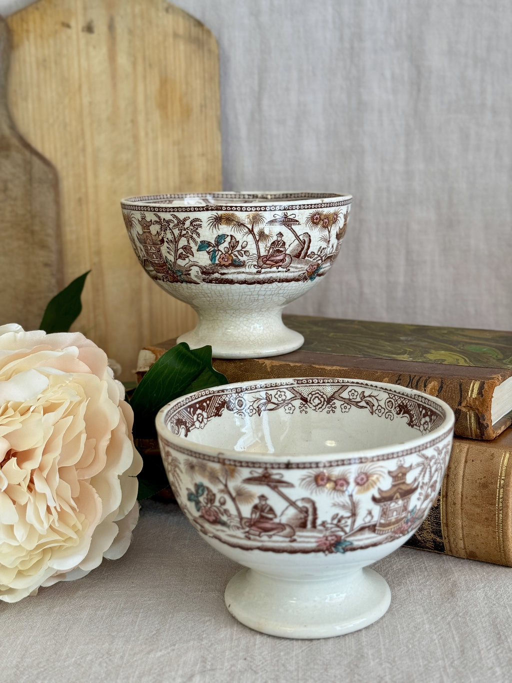 Pair of French brown transferware café au lait bowls styled on antique books with a peony and a bread board