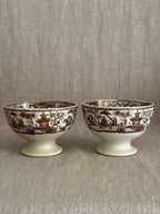 Both bowls seen from the side, showing the brown transfer band and pedestal feet