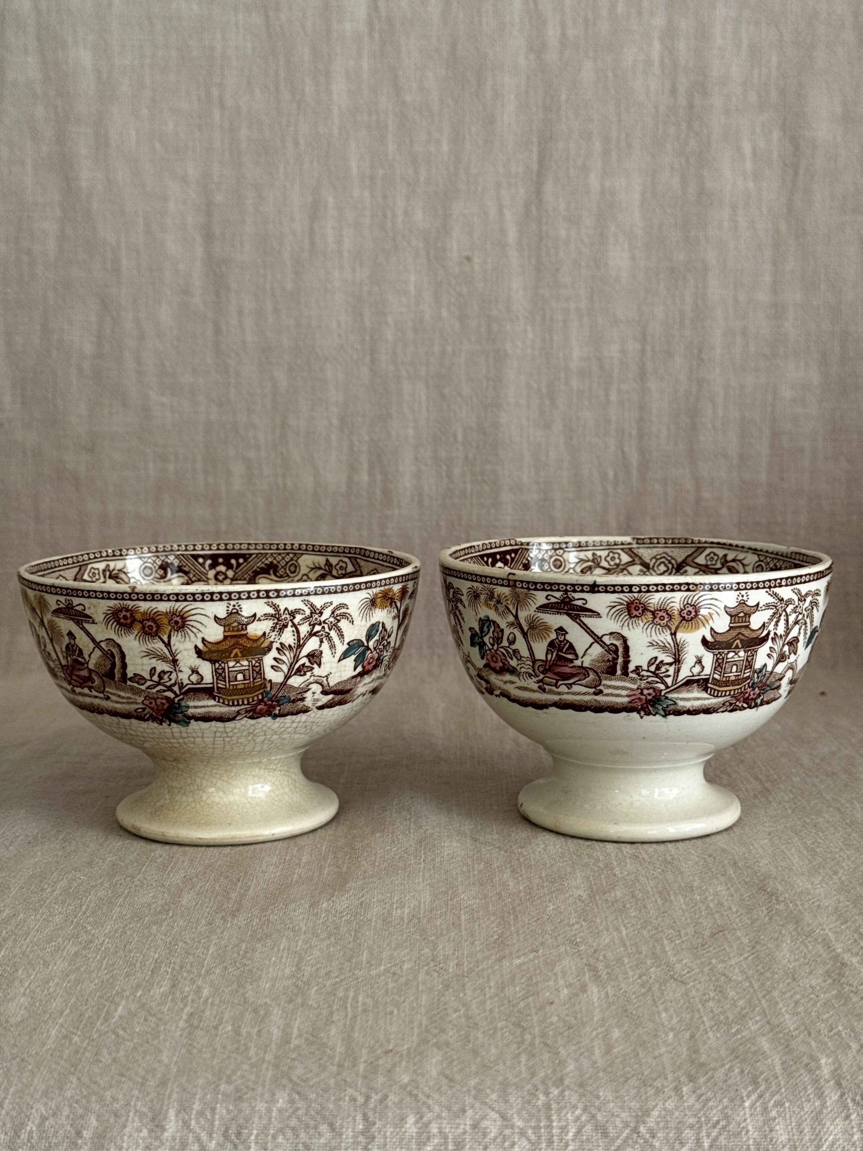 Both bowls seen from the side, showing the brown transfer band and pedestal feet