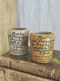 Pair of French Maille stoneware mustard pots, one ochre and one cream, standing on antique books