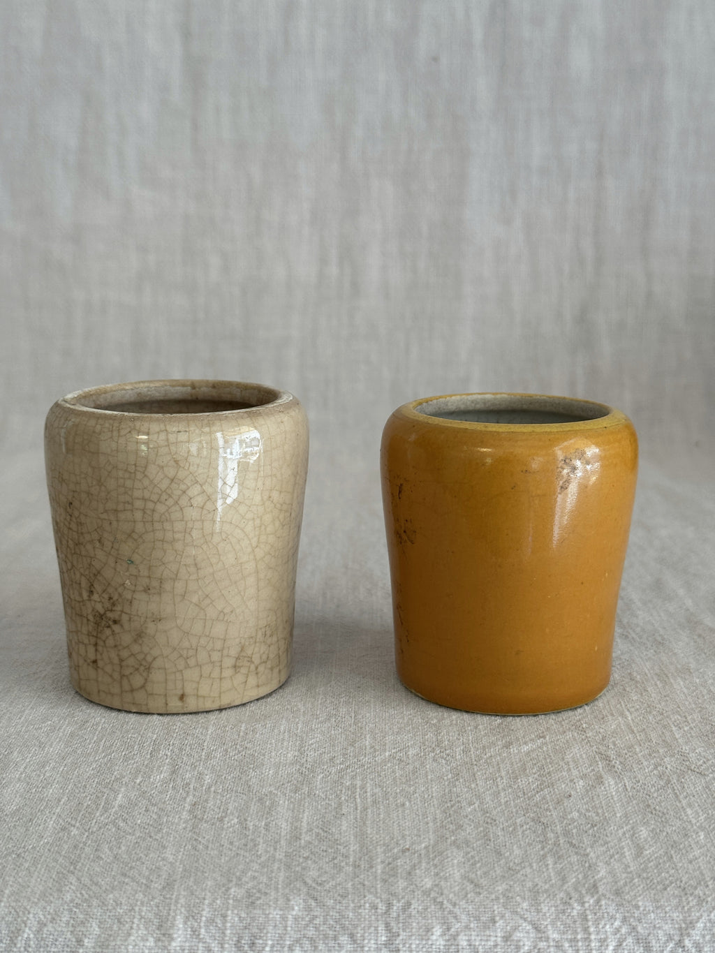 The two pots seen from another angle, the ochre glaze against the plain cream stoneware