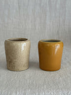 The two pots seen from another angle, the ochre glaze against the plain cream stoneware