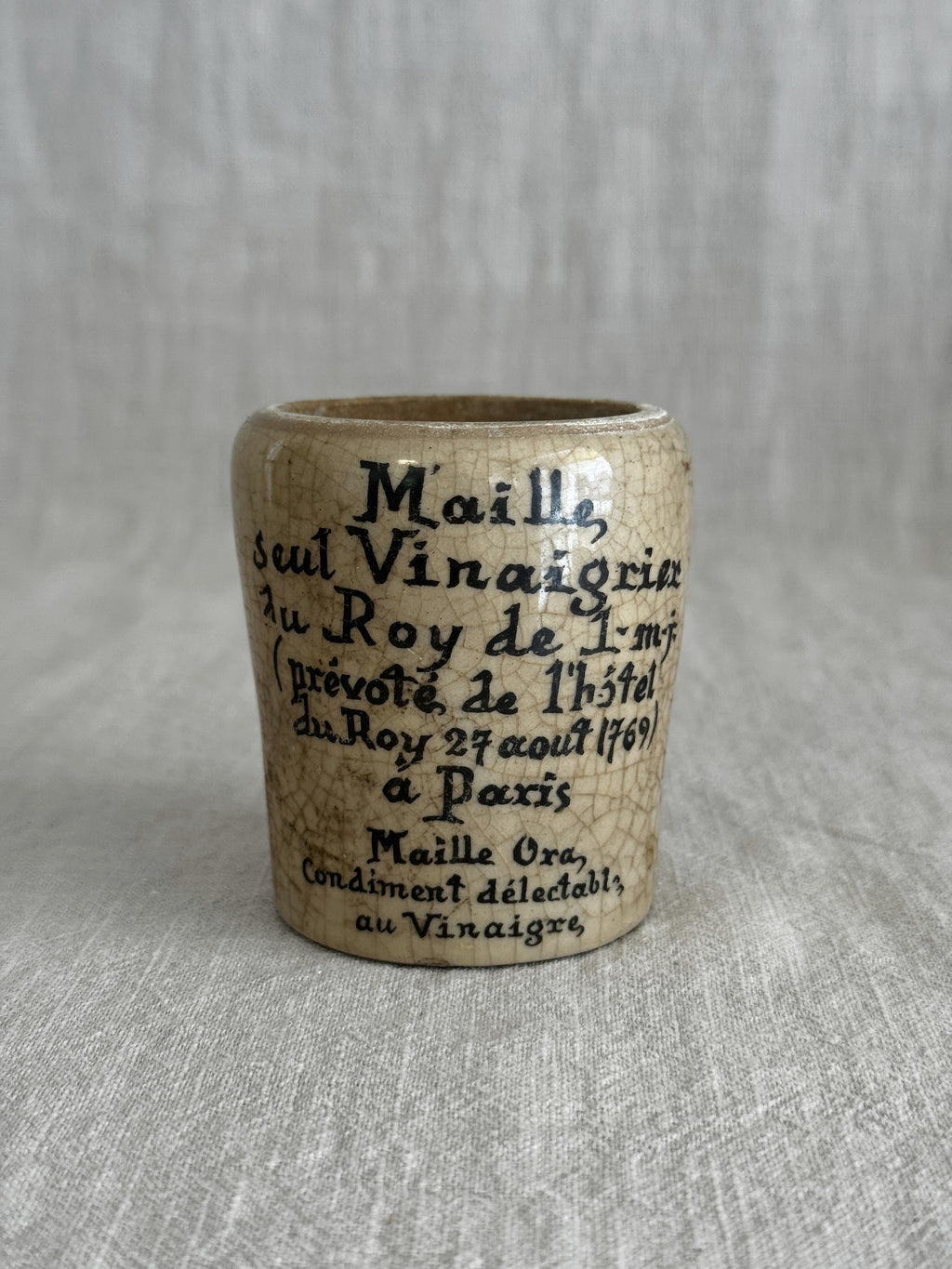 Close view of the ochre glazed pot showing the printed text and warm yellow glaze