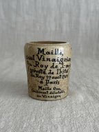 Close view of the ochre glazed pot showing the printed text and warm yellow glaze