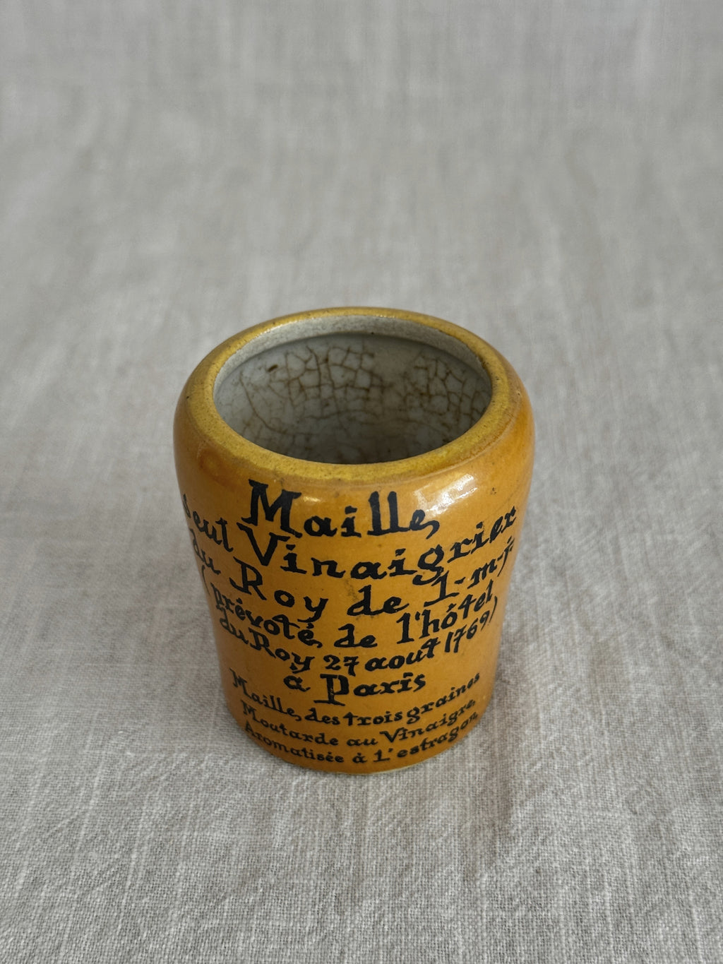 Close view of the ochre pot on its side with the full printed lettering visible