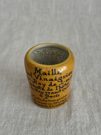 Close view of the ochre pot on its side with the full printed lettering visible