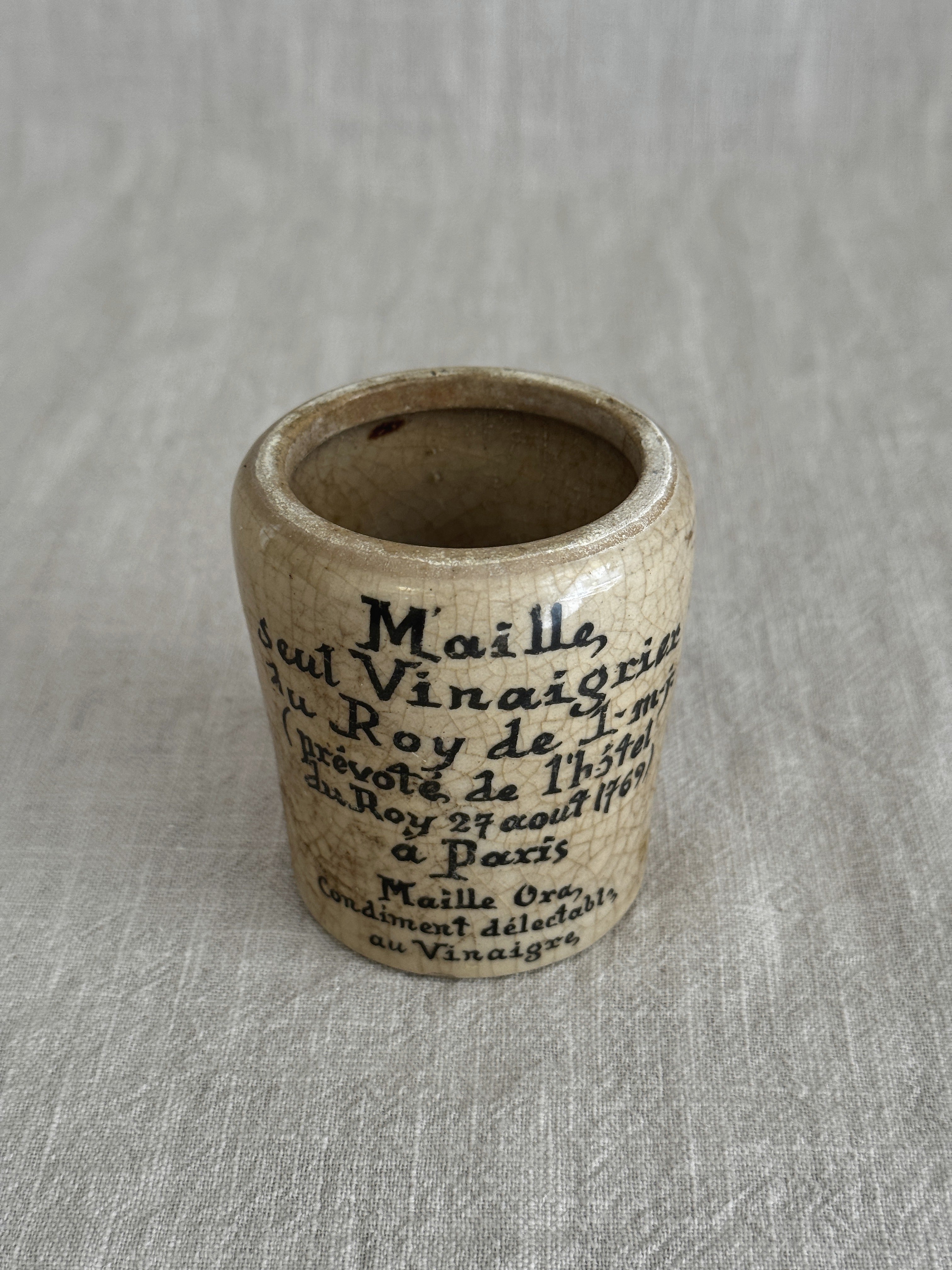 The cream Maille pot photographed close, showing the crisp printed text and patina
