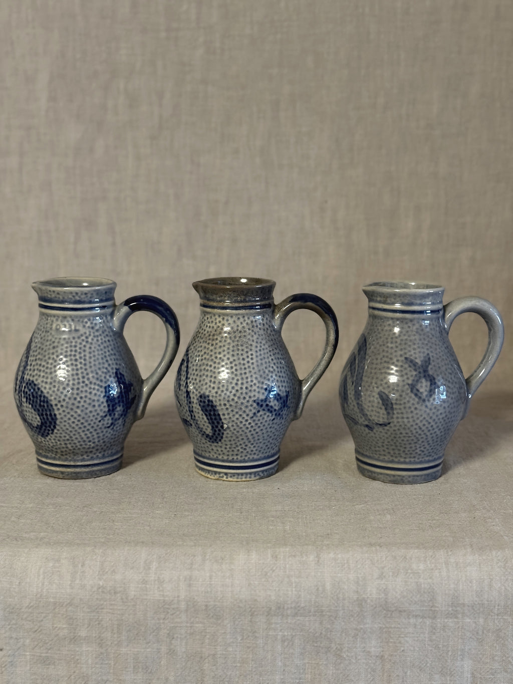 The three jugs seen together from a slightly different angle on linen