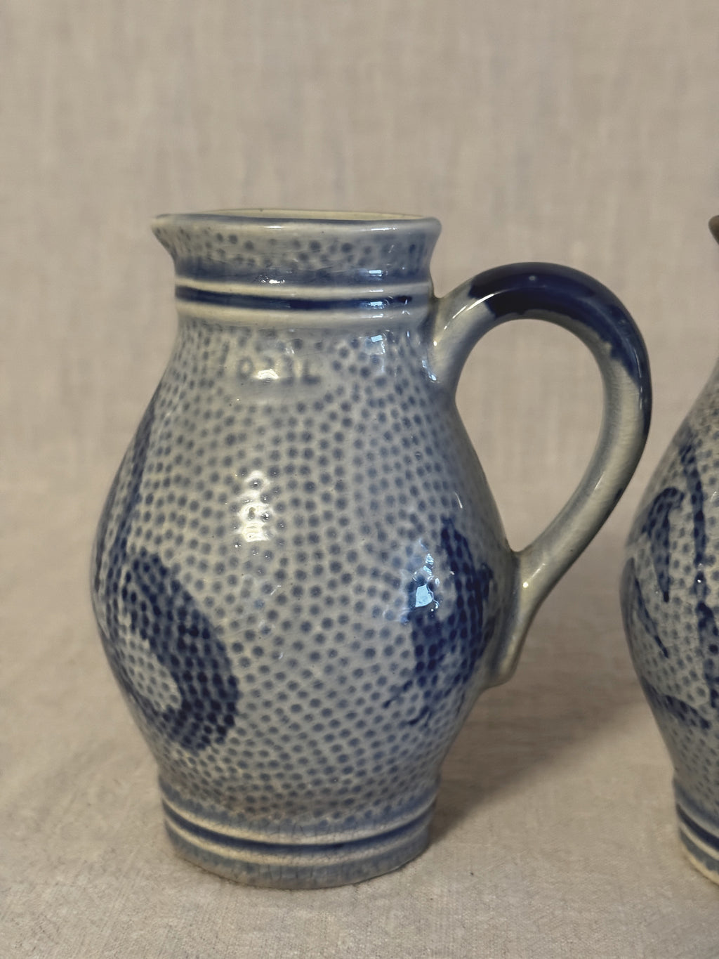 Side view of one jug showing the loop handle and cobalt banding at the collar