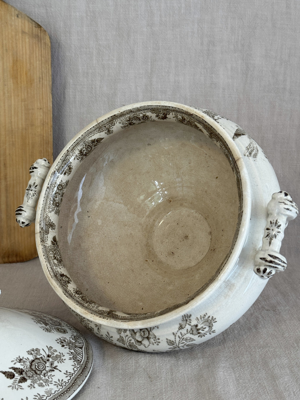 Interior of the antique Swedish earthenware tureen in tea-softened ivory, lid resting alongside
