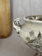 Close view of a pierced rosette handle terminal with hand-painted brown accents on the antique tureen
