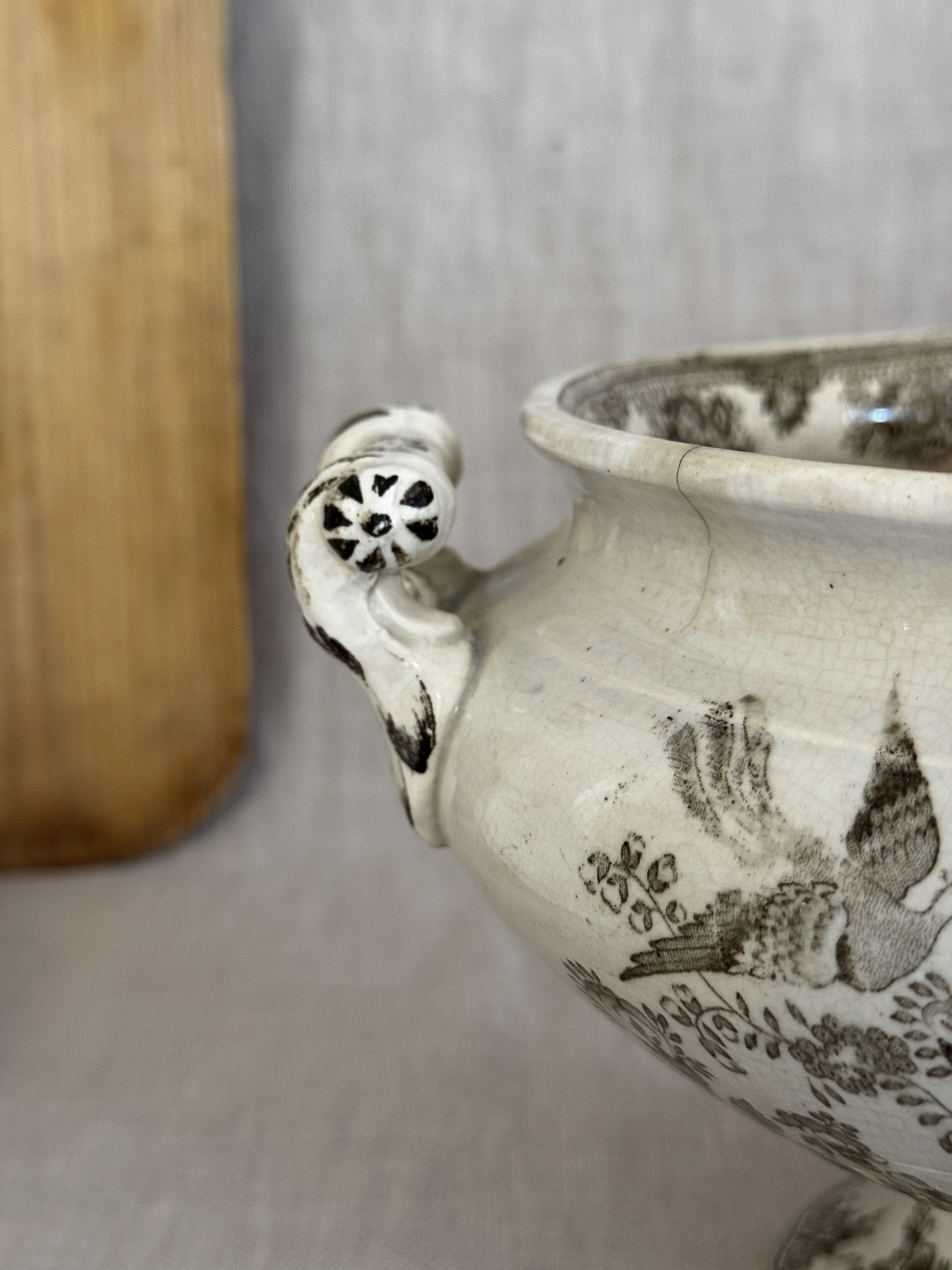 Close view of a pierced rosette handle terminal with hand-painted brown accents on the antique tureen