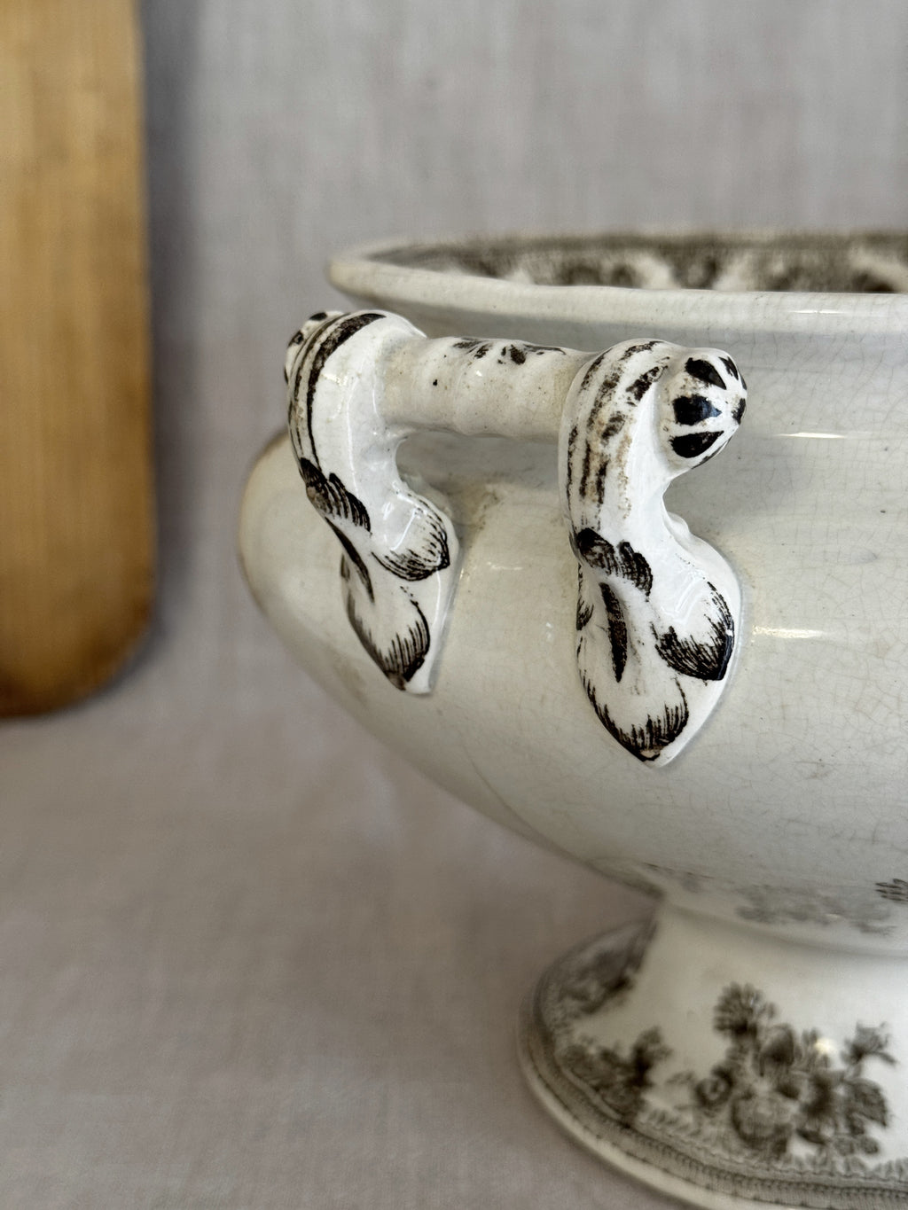 Detail of the hand-modelled scroll handles and the tall trumpet foot of the antique Swedish tureen