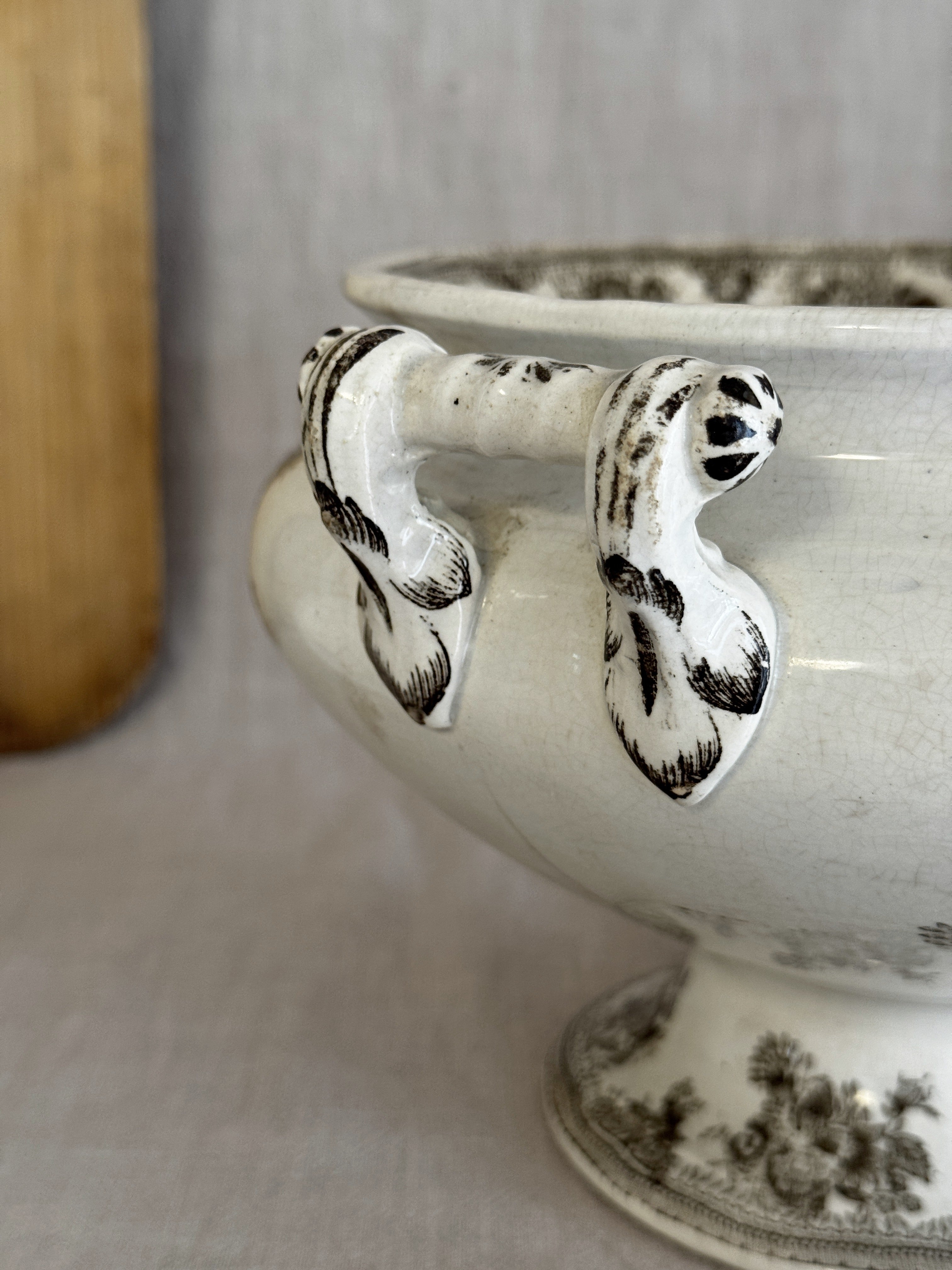Detail of the hand-modelled scroll handles and the tall trumpet foot of the antique Swedish tureen