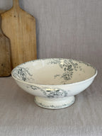 Antique Choisy-le-Roi footed salad bowl seen from the side on a linen cloth, with a wooden board behind