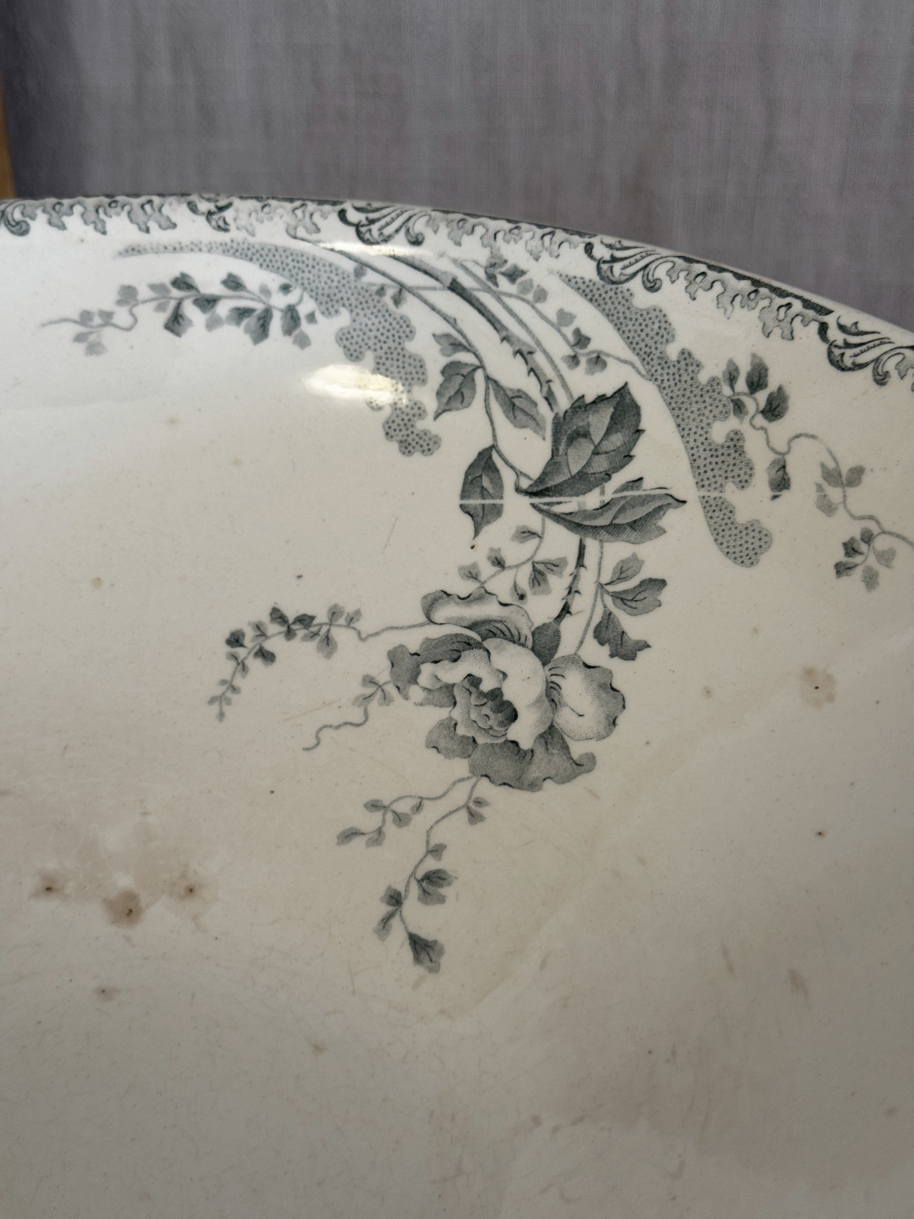 Close detail of the sage green rose transfer inside the antique French bowl, with light iron spotting in the glaze