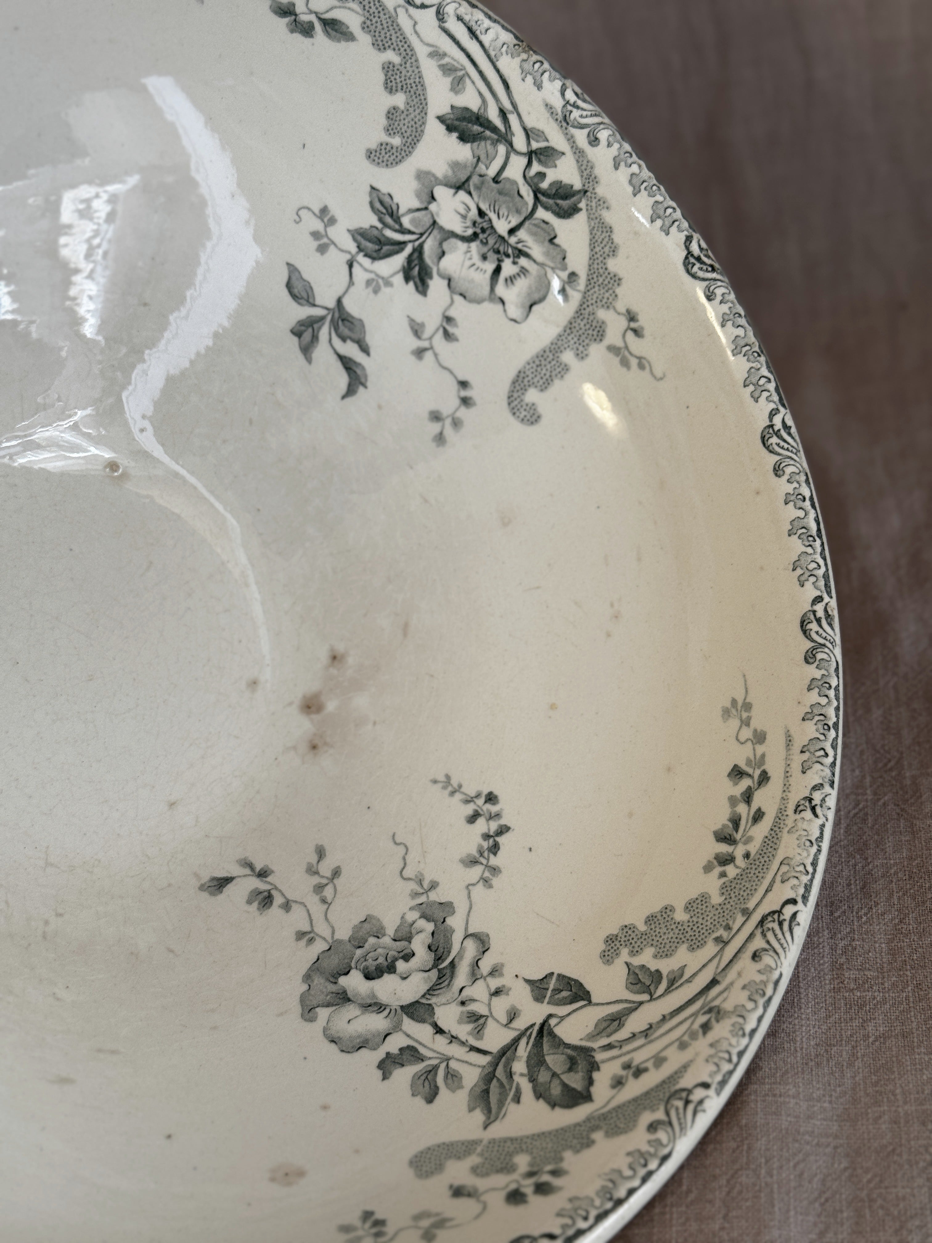 Interior rim of the antique terre de fer saladier, showing the scrolled border and floral transfer