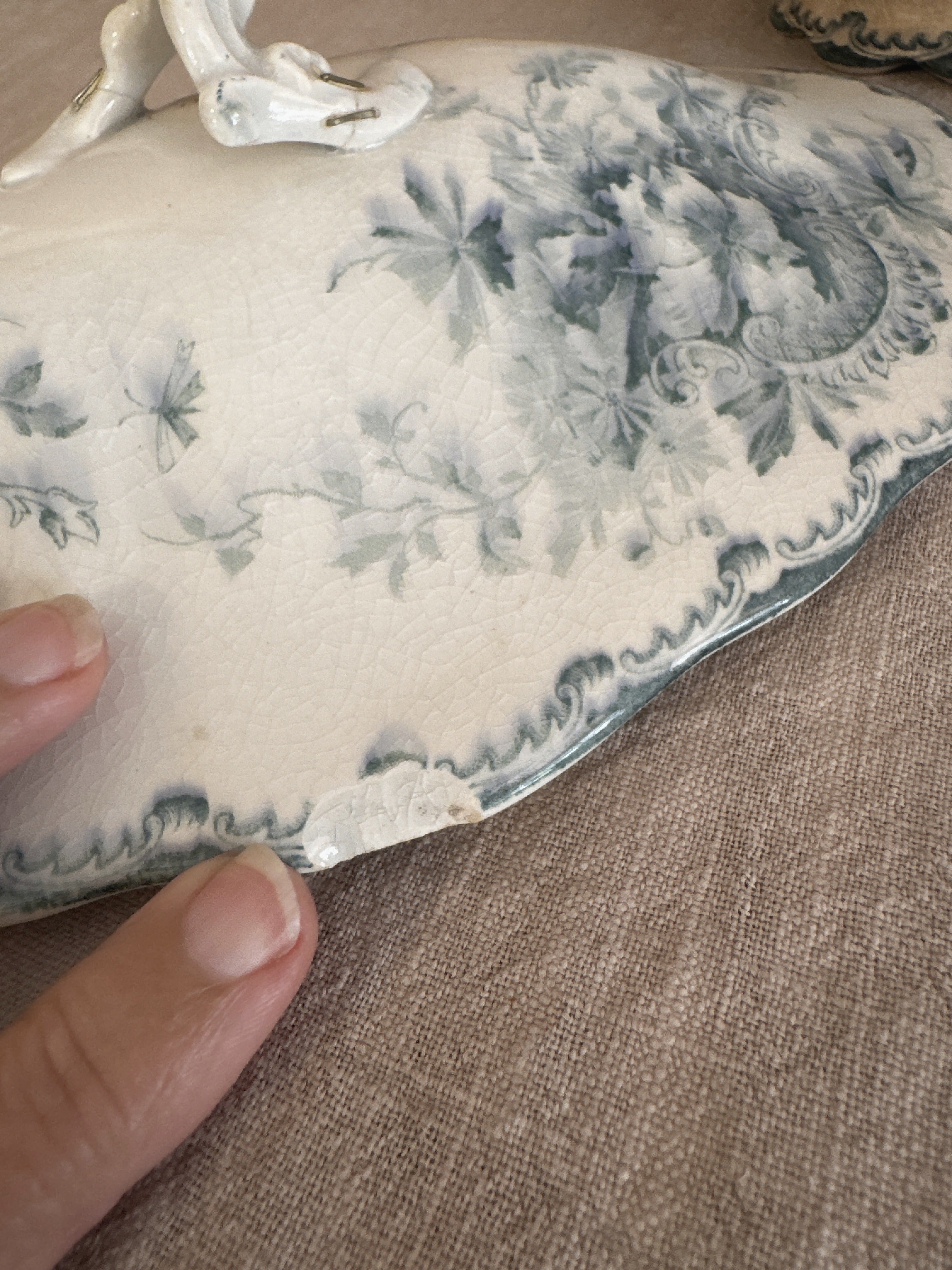 Wave-cut edge of the tureen lid showing the glaze, crazing and teal floral transfer
