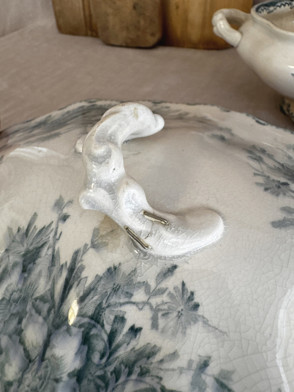 Metal staples set into the sculpted branch finial of the Swedish transferware lid