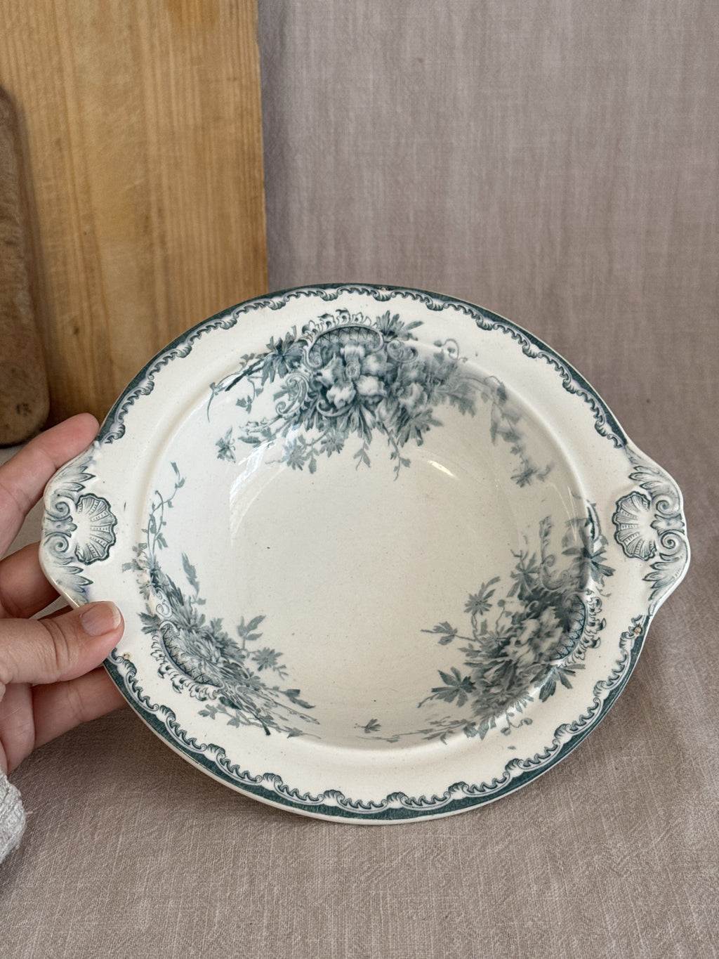 Round Swedish transferware serving bowl held in the hand, shell handles and wave-cut rim