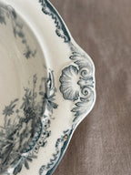 Close view of a moulded shell handle and the teal rocaille border on the earthenware rim
