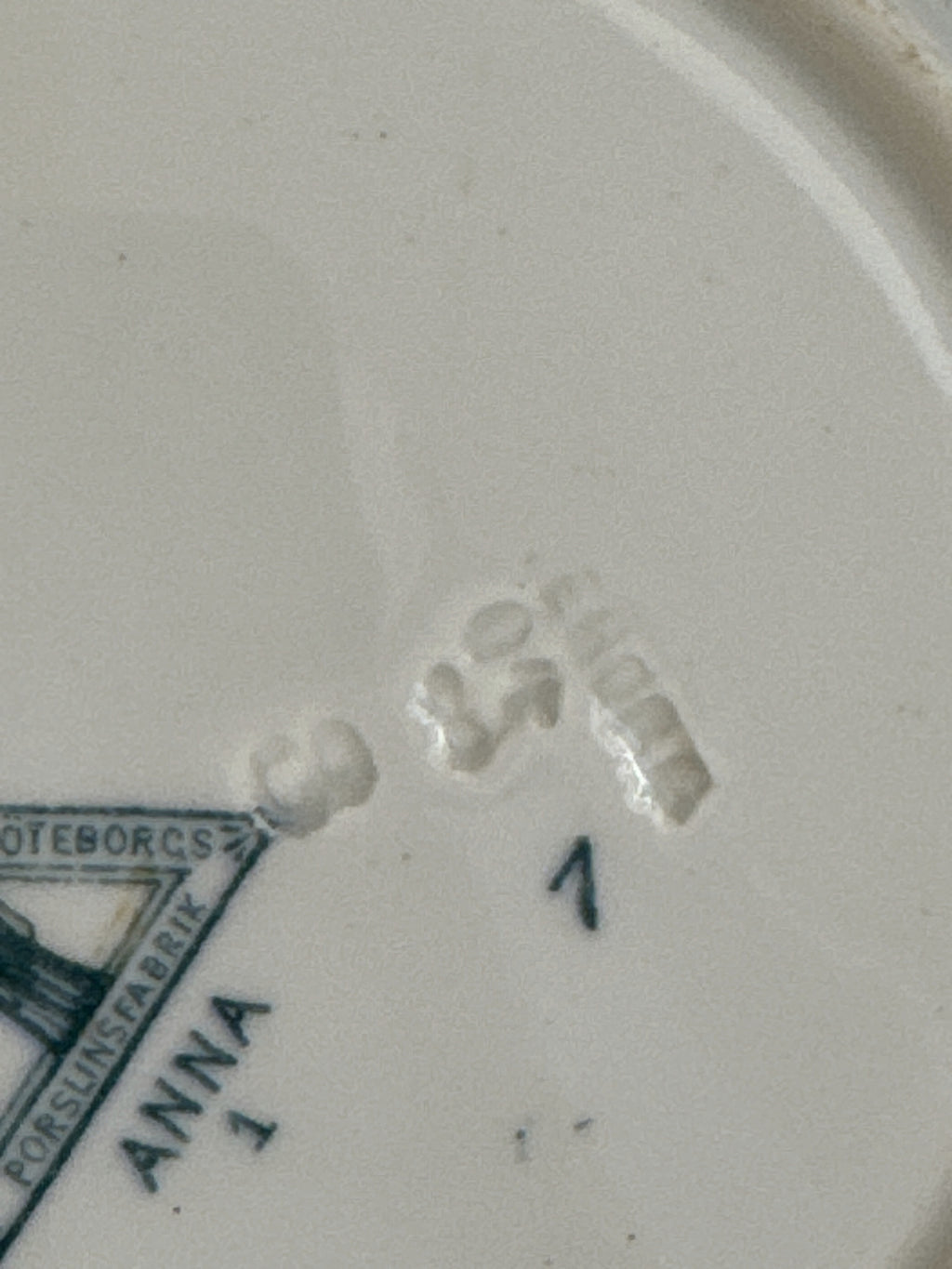Close view of the printed ANNA mark and the impressed marks on the underside