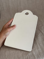 Matt bisque reverse of the white faience board, held in a hand for scale
